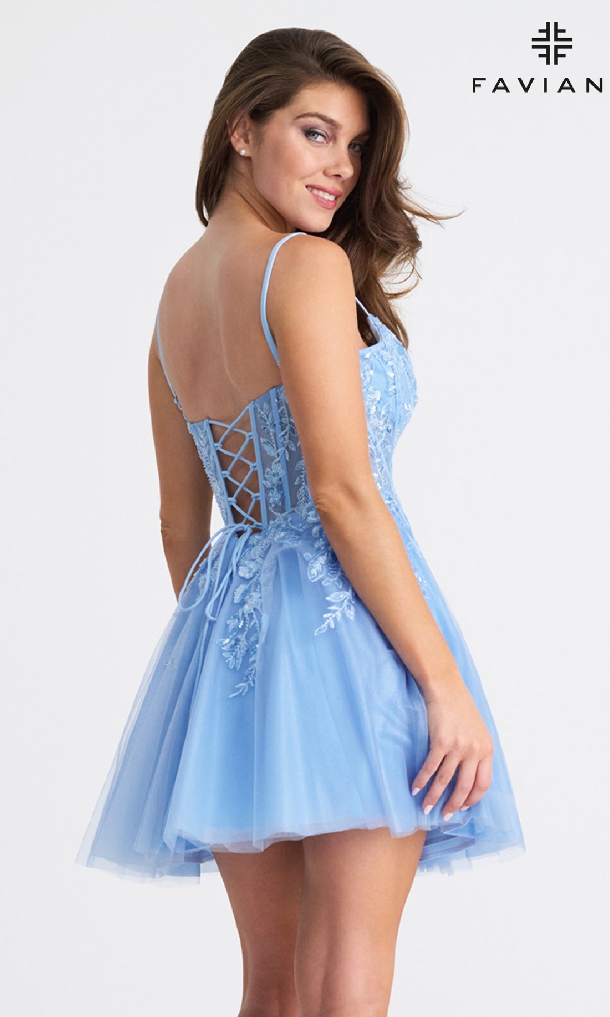 A woman stands looking over her shoulder in the Faviana 11305 Short Fit-and-Flare Hoco Dress, a light blue sleeveless homecoming dress with beaded floral appliqué.